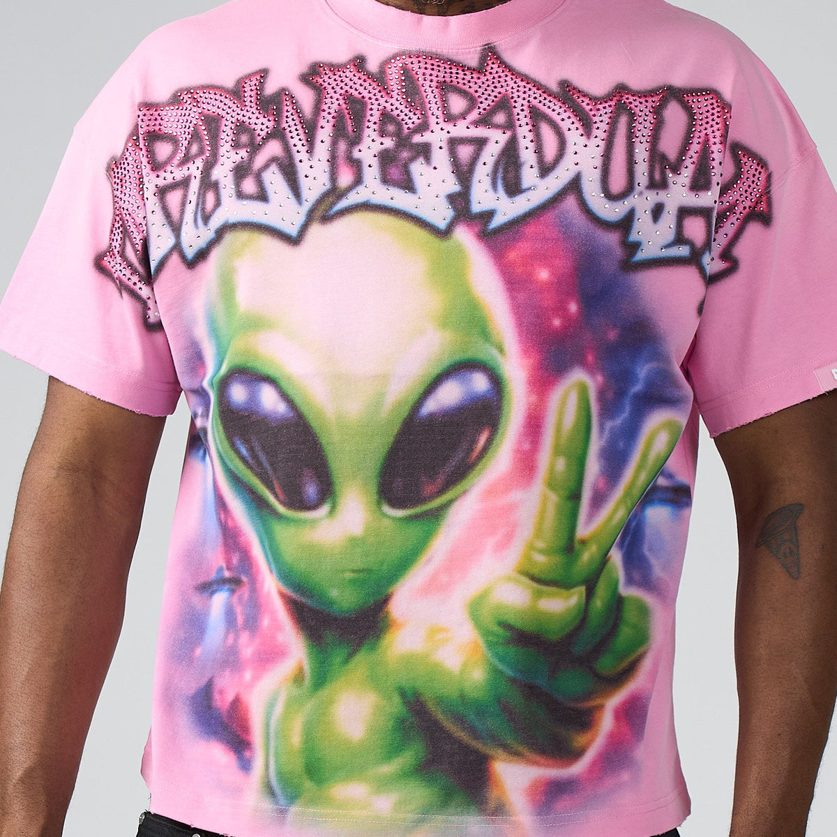 Person wearing a pink t-shirt with an alien graphic and text on a gray background