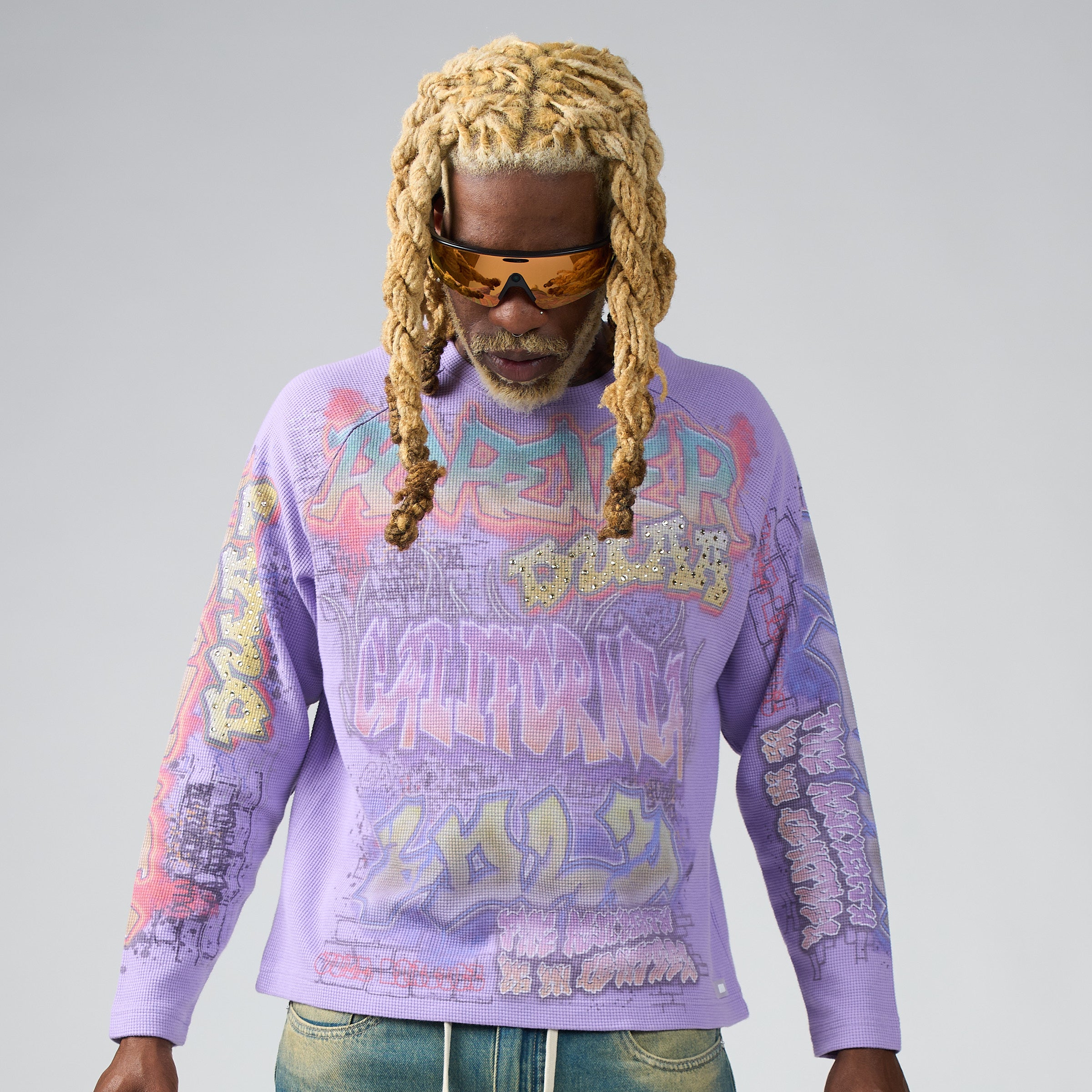 Person wearing a DUAA purple graphic sweatshirt with colorful text and designs on a plain background