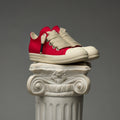 DUAA Red and beige sneakers on a decorative column against a gray background