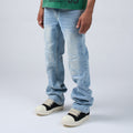 A person wearing DUAA light-wash distressed denim jeans with cuffed hems and black-and-cream platform sneakers, shown from the waist down against a light gray studio background.